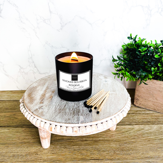 Masculine scented candle named Smoked Bourbon Reserve on wood surface with warm ambient lighting"
